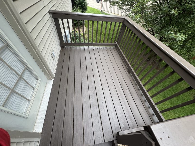 Small gray-stained deck landing at the top of an exterior stairway, hand-applied by TD Surface Stain and Seal