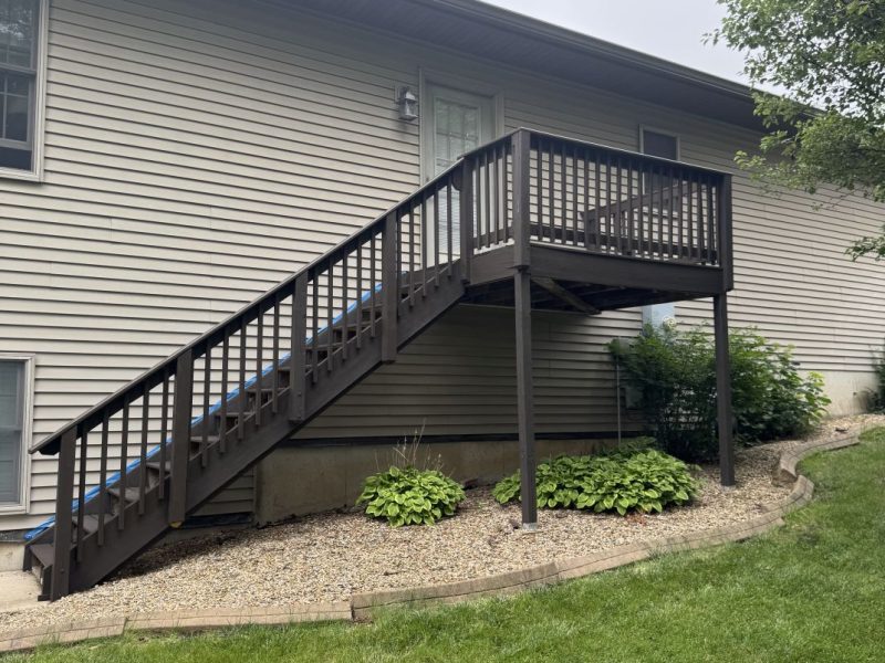 Elevated deck with dark brown stained stairs and railings at a small home, hand-applied by TD Surface Stain and Seal