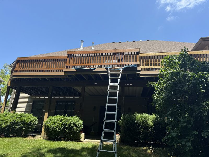 Deep brown stained deck structure with a ladder set up during a staining project by TD Surface Stain and Seal