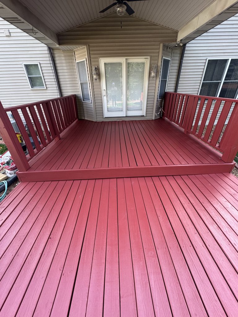 Close-up of a rich red solid-stain finish on deck boards showing the even hand-applied coverage by TD Surface Stain and Seal