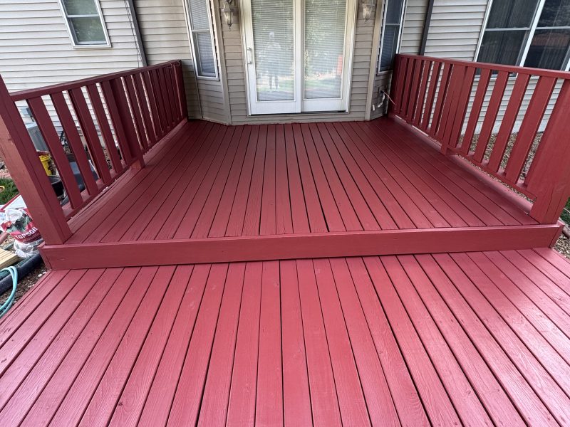 Close-up of a rich red solid-stain finish on deck boards showing the even hand-applied coverage by TD Surface Stain and Seal