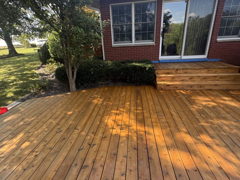 Beautiful cedar-toned stained deck at a brick home with steps and landscaping, hand-applied by TD Surface Stain and Seal Springfield IL