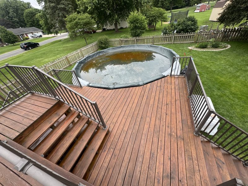 Elevated wood deck with warm brown stain overlooking an above-ground pool, hand-applied finish by TD Surface Stain and Seal