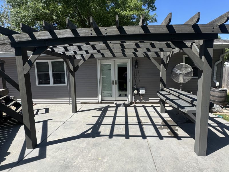 Gray-stained wood pergola over a concrete patio at the back of a home, finished by TD Surface Stain and Seal