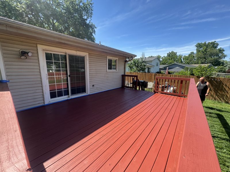 Large deck with rich red solid stain finish at the back of a home, hand-applied by TD Surface Stain and Seal