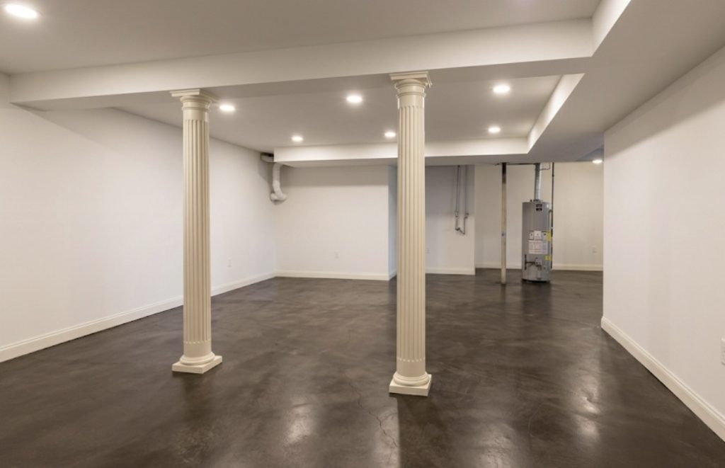Finished basement featuring a rich stained and sealed concrete floor with white decorative pillars, concrete staining by TD Surface Stain and Seal