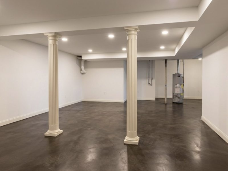 Finished basement featuring a rich stained and sealed concrete floor with white decorative pillars, concrete staining by TD Surface Stain and Seal